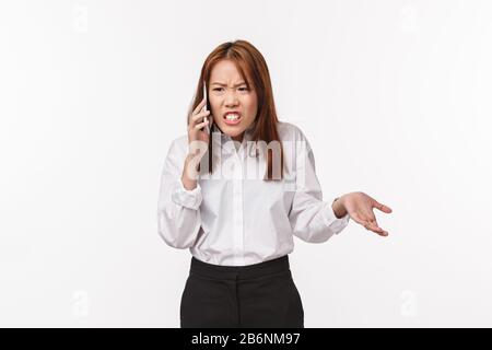Portrait d'une femme asiatique en colère insatisfaite parlant au téléphone, agacant et indignée, ayant de graves conversations difficiles, argumentaire avec le partenaire Banque D'Images