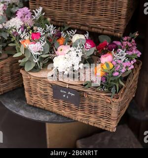 Bouquet de ranunculus blanc, daisies rouges, eucalyptus, hyacinthes bleus, cerise blanche dans une boîte de saule en osier à vendre Banque D'Images