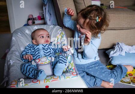 Jeune fille de 3 ans jouant avec son frère de bébé de 3 mois Banque D'Images