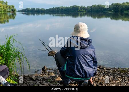 Le jeune garçon attrape du poisson avec la tringle de pêche sur la rivière après la pluie Banque D'Images