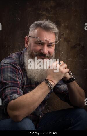 Portrait studio d'un homme barbu d'âge moyen à poil gris souriant à l'appareil photo, mise au point sélective Banque D'Images