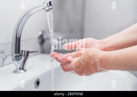 femme nettoyant ses mains avec du savon sur le robinet pour protéger contre le virus Banque D'Images