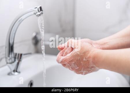 femme nettoyant ses mains avec du savon sur le robinet pour protéger contre le virus Banque D'Images