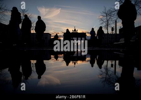 Berlin, Allemagne. 11 mars 2020. Passants à pied sur Pariser Platz au crépuscule devant la porte de Brandebourg. Le paysage se reflète dans une flaque. Crédit: Christoph Soeder/Dpa/Alay Live News Banque D'Images