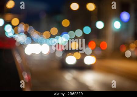 La voiture monte sur une route de la ville en bokeh la nuit. Circulation en soirée Banque D'Images