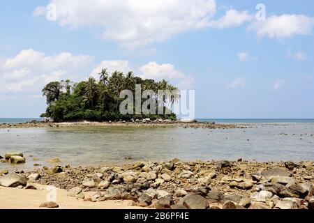 Île tropicale avec palmiers à noix de coco dans un océan, vue pittoresque de la plage avec des rochers. Paysage marin coloré avec ciel bleu et nuages blancs Banque D'Images