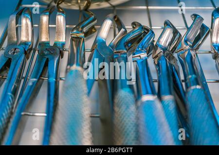 Outils dentaires professionnels. Pince d'extraction des dents supérieures en gros plan sous la lumière de lampes de chambre bactéricides. Mise au point douce Banque D'Images