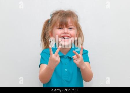 Une petite fille qui se colle à 2 doigts vers le haut Banque D'Images