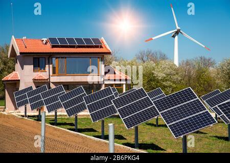 Panneaux solaires sur le toit d'une maison familiale, photovoltaïque avec systèmes de suivi solaire dans la cour et éolienne - concept de sources d'énergie renouvelables Banque D'Images