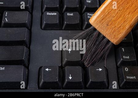 Nettoyez le clavier de la poussière et de la saleté à l'aide d'une brosse. Maintenance et nettoyage du matériel informatique. Fond sombre. Banque D'Images