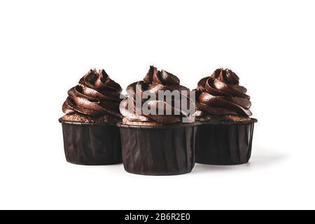 Trois délicieux cupcakes au chocolat avec des taches d'or saupoudrés de glaçage au chocolat sur fond blanc isolé. Maquette pour votre conception. Gros plan. Pla Banque D'Images