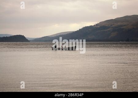 Un bateau amarré dans une baie éloignée du Loch Lomond dans les Highlands écossais pendant une journée d'hiver Banque D'Images