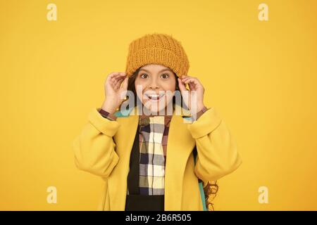 Bonnet hiver accessoire. Des cheveux longs de fille fond jaune. Saison froide concept. Accessoire de mode d'hiver. Petit enfant portant chapeau chaud. Choisissez entre plus mignonne et la plus branchée. Kid girl porter chapeau tricoté. Banque D'Images