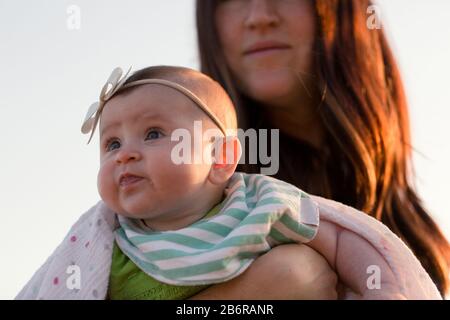 Une mère et son bébé s'arrêtent et sentent les fleurs. Banque D'Images