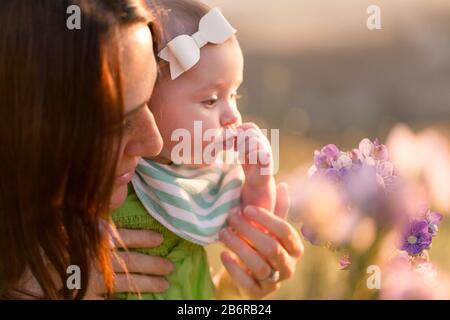 Une mère et son bébé s'arrêtent et sentent les fleurs. Banque D'Images