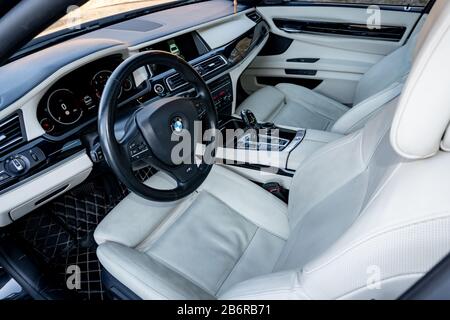 Sièges intérieurs en cuir blanc et tableau de bord à l'intérieur d'une luxueuse limousine noire BMW 750 d avec 381 ch, équipement de confort haute technologie. Forfait M et individuel Banque D'Images