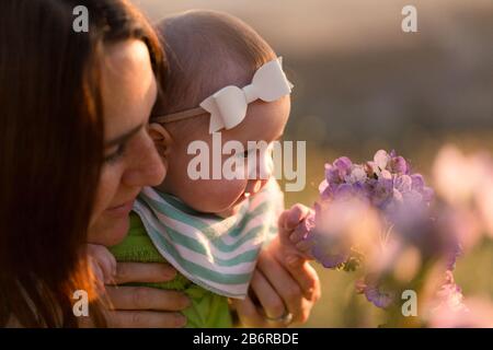 Une mère et son bébé s'arrêtent et sentent les fleurs. Banque D'Images