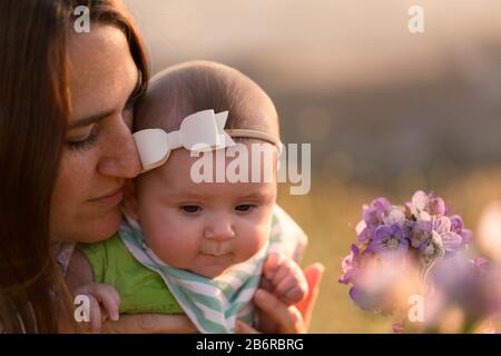 Une mère et son bébé s'arrêtent et sentent les fleurs. Banque D'Images