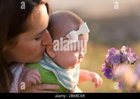 Une mère et son bébé s'arrêtent et sentent les fleurs. Banque D'Images