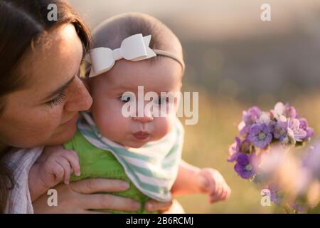 Une mère et son bébé s'arrêtent et sentent les fleurs. Banque D'Images