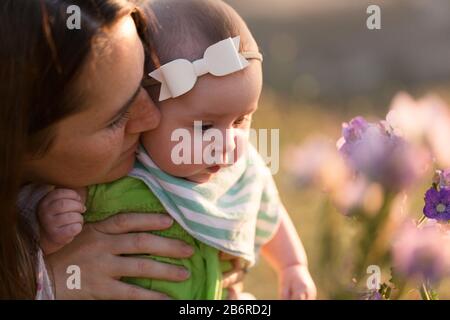 Une mère et son bébé s'arrêtent et sentent les fleurs. Banque D'Images