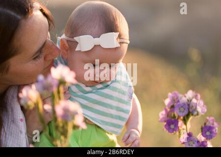 Une mère et son bébé s'arrêtent et sentent les fleurs. Banque D'Images