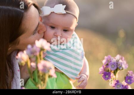 Une mère et son bébé s'arrêtent et sentent les fleurs. Banque D'Images