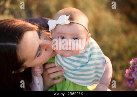 Une mère et son bébé s'arrêtent et sentent les fleurs. Banque D'Images