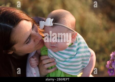 Une mère et son bébé s'arrêtent et sentent les fleurs. Banque D'Images