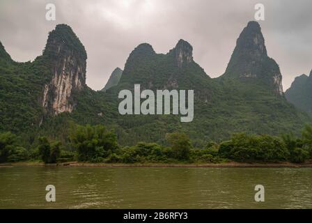 Guilin, Chine - 10 Mai 2010 : Le Long De La Rivière Li. Paysage où de grandes montagnes karstiques avec des falaises semblent être placées dans une forêt dense de pluie verte sous les brownis Banque D'Images