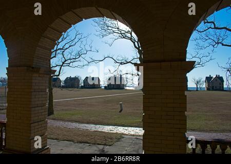 Les silhouettes des maisons de rangée de l'officier bordant la rive de Sandy Hook Bay sont vues du portique d'un bâtiment inoccupé derrière elles Banque D'Images