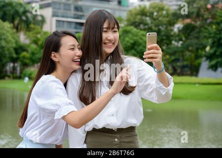 Deux jeunes filles adolescentes asiatiques joyeuses qui se rassemblent ensemble dans le parc Banque D'Images