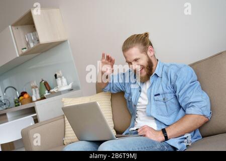 Jeune homme heureux ordinateur portable moderne chat en ligne vague bonjour appels vidéo de la maison. Banque D'Images