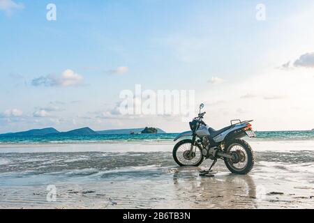 Une moto argentée se trouve sur la plage Banque D'Images