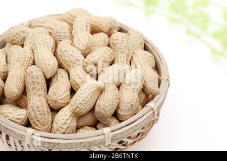 Arachides biologiques en coquille dans un panier de bambou sur fond blanc Banque D'Images