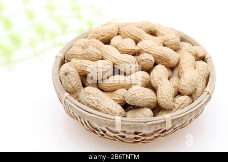 Arachides biologiques en coquille dans un panier de bambou sur fond blanc Banque D'Images