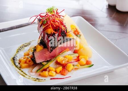 Ahi Tuna Cajun poêlé avec croûte de sésame, salade de salsa à la mangue aigre-douce et pommes de terre cuites sur une plaque blanche Banque D'Images