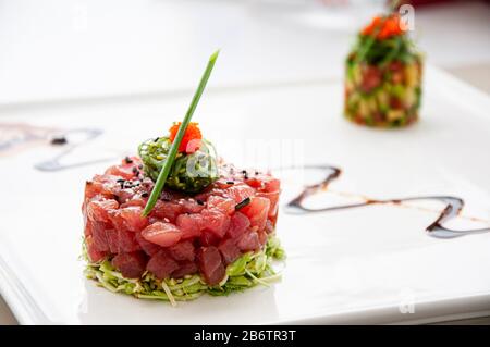 Tartare de thon frais aux algues de sésame et salade verte, sauce réduction balsamique et salsa aux fruits tropicaux en plaque blanche Banque D'Images