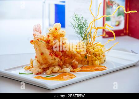 Crevettes tigrées épicées et frites croustillantes avec salsa à la mangue et sauce aux mille piments chauds sur la plaque blanche Banque D'Images