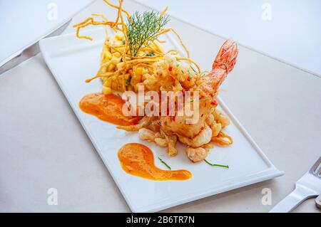 Crevettes tigrées épicées et frites croustillantes avec salsa à la mangue et sauce aux mille piments chauds sur la plaque blanche Banque D'Images