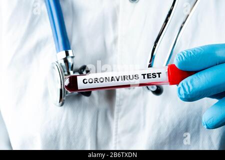 Concept de test sanguin du coronavirus. Analyse de l'échantillon sanguin dans le tube à essai pour l'essai de coronavirus dans la main du médecin. Tube de test avec sang pour l'analyse 2019-nCoV. Banque D'Images