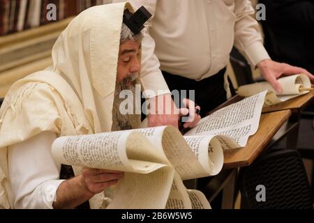 Le juif ultra orthodoxe enveloppé de Talit shawl religieux traditionnel et de la técilline des phylactères lit la Mégillah ou le Scroll d'Esther pendant le festival juif de Purim dans la vieille ville de Jérusalem-est Israël Banque D'Images