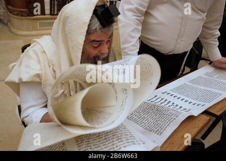 Le juif ultra orthodoxe enveloppé de Talit shawl religieux traditionnel et de la técilline des phylactères lit la Mégillah ou le Scroll d'Esther pendant le festival juif de Purim dans la vieille ville de Jérusalem-est Israël Banque D'Images