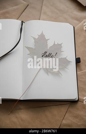 Le mot bonjour dans le bloc-notes et la feuille d'érable. Bonjour concept automne Banque D'Images