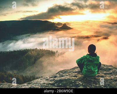 Le randonneur féminin fait une pause et jouit d'une vue sur la montagne. Randonneur féminin assis sur le bord de crête et profitant de la vue sur la vallée des montagnes pendant le salon de la ville de Tsbie2 Banque D'Images