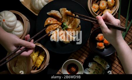 Vue de dessus de deux femelles mangeant Dim Sum avec des boulettes de gyoza japonaises frites, des boulettes chinoises, des boulettes de porc aux œufs salés et des petits pains au restaurant chinois Banque D'Images