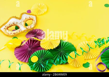 Papier coloré confetti, masque carnivale et serpentine colorée sur un fond jaune avec espace de copie, carte de vœux et modèle d'invitation de fête des Banque D'Images