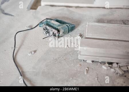 Une scie sauteuse électrique est posée sur le sol. Plaque de gypse. Construction de murs internes dans l'appartement à l'aide d'une plaque de béton en plâtre avec rainure Banque D'Images