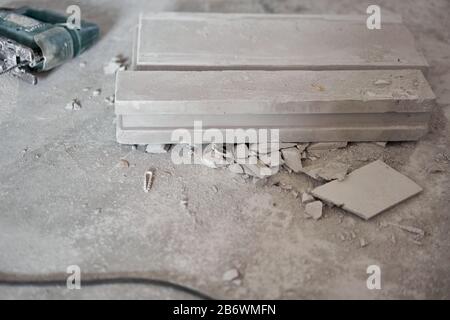 Une scie sauteuse électrique est posée sur le sol. Plaque de gypse. Construction de murs internes dans l'appartement à l'aide d'une plaque de béton en plâtre avec rainure Banque D'Images