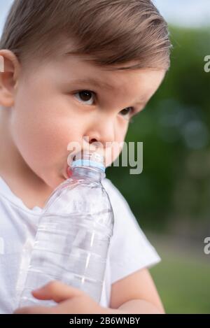 Beau bébé boit de l'eau propre à partir d'une bouteille sur une journée ensoleillée dans la nature Banque D'Images